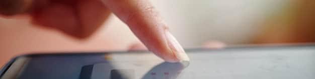 A close-up of a person's hand selecting privacy settings on a tablet. The interface displays options like 