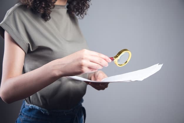 Close-up shot of a hand holding a pen, hovering over a tax form with magnifying glass placed on top. The focus is on the details of the form and the act of careful review and analysis.