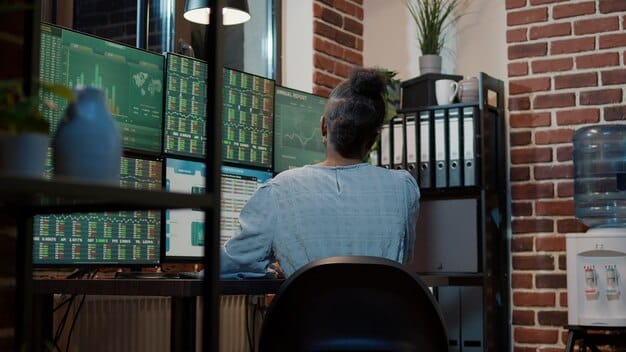 A network security analyst working at a desk with multiple monitors displaying complex network diagrams and security alerts. The analyst is focused and intently studying the data.